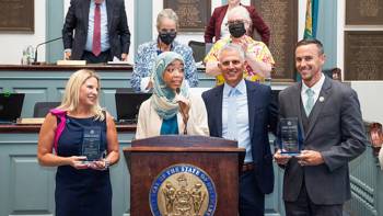 A man and a woman receive an award in front of a podium